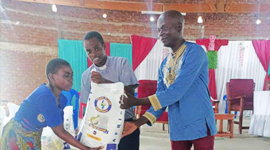 Rev. Kwalamasa presenting a bag of maize flour